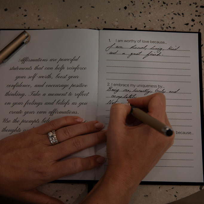 Person writing in the Lusté journal with a Lusté branded pen 